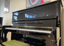 Seiler piano, model Concert 132cm in zwart hoogglans met ovaal in het bovenraam en Renner mechaniek met SMR-systeem (Super Magnet Repetition) waarmee een vleugelrepetitie behaald kan worden. (ook onderin de toets) Bouwjaar 2005